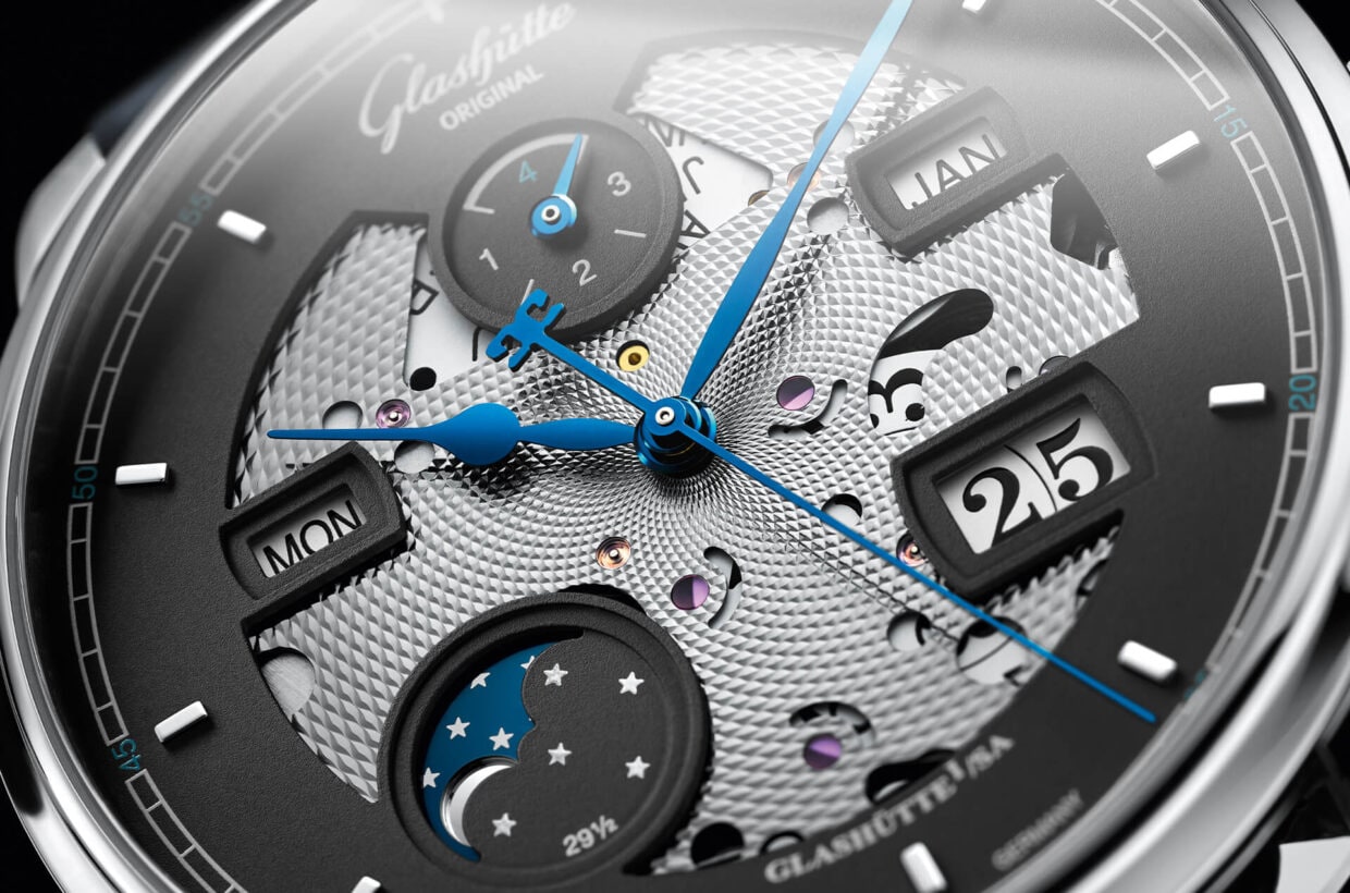 Deep insights Artfully skeletonized dial, recessed displays for the Panorama Date, moon phase, week day, month and leap year, movement cover plate decorated in the centre with a guilloche pattern, visible red rubies 
